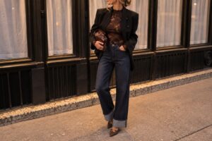 Look autunnale da donna con jeans wide leg blu, blazer scuro e accessori marroni, per un outfit casual chic dal raffinato stile urbano.