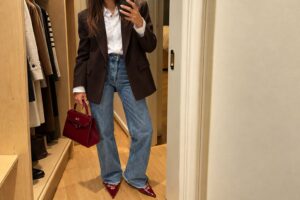 Outfit autunnale casual chic con jeans wide leg blu, camicia bianca, blazer marrone e accessori bordeaux, per un look femminile elegante e di tendenza.